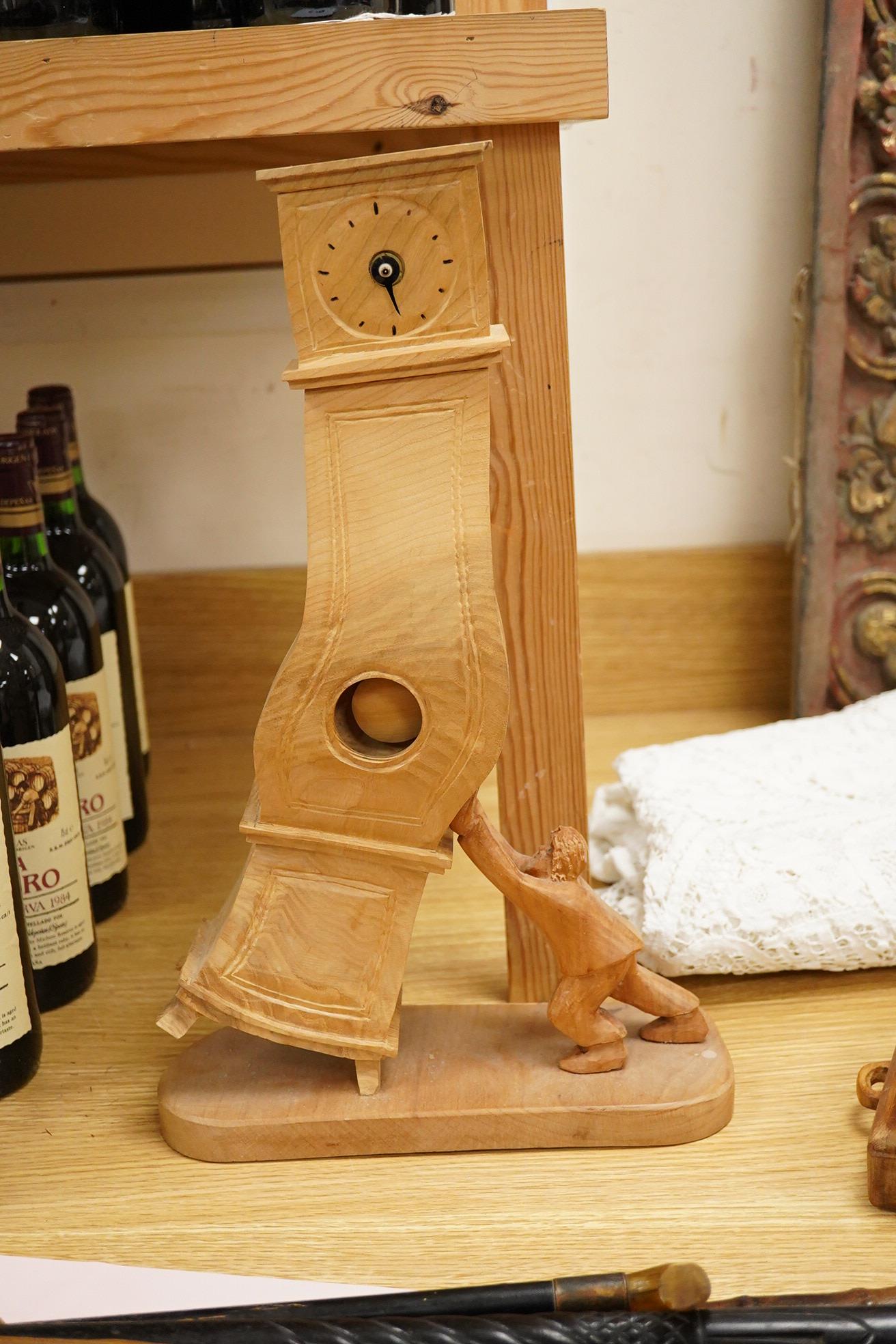 Pierre Decorse (b.1953), a naturalistically modelled wooden sculpture of a grandfather clock and a figure, together with two other sculptures comprising a suitcase and figure, largest 42cm high